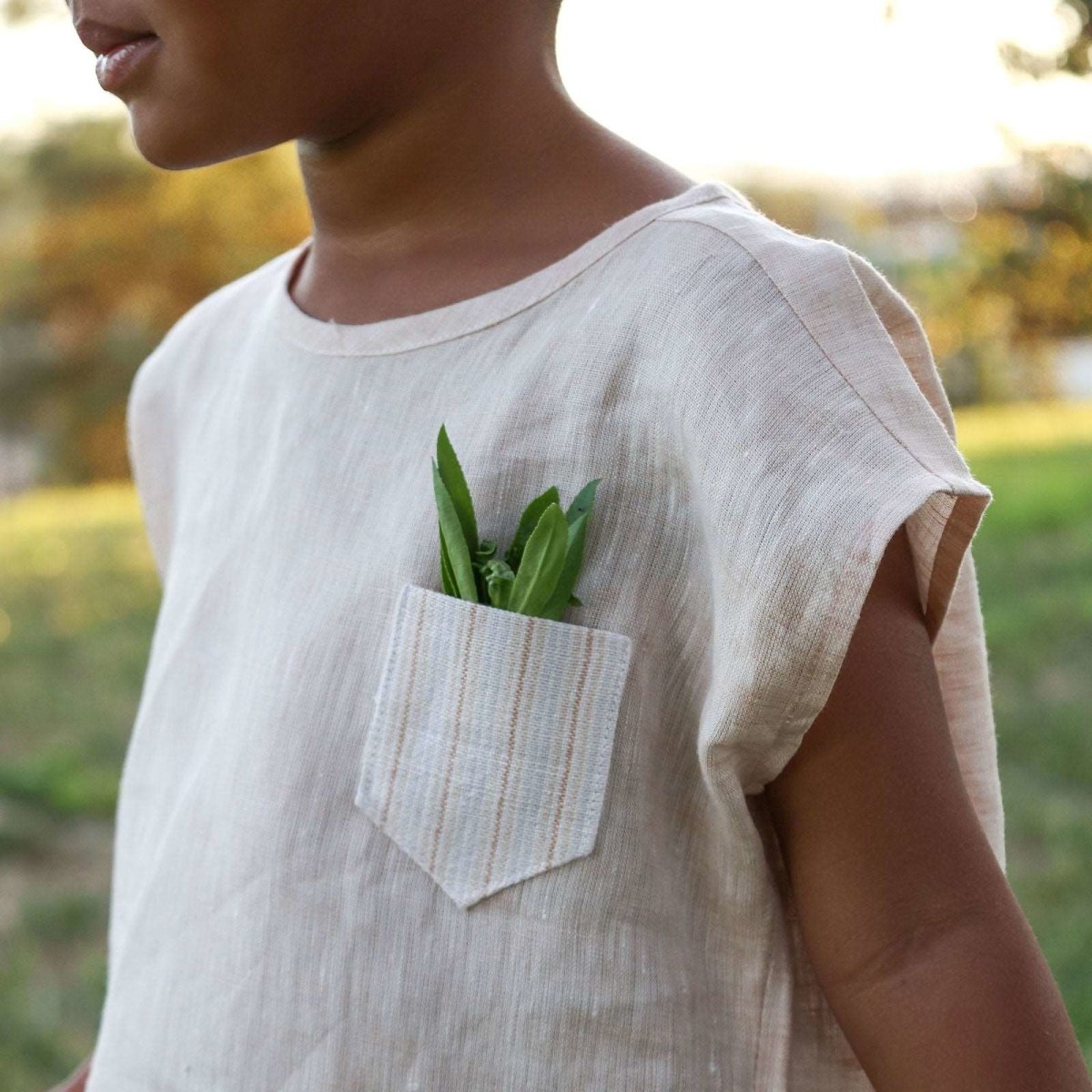 detail view of Beya Made linen box top worn by 3 year old girl with leaves sticking out of pocket