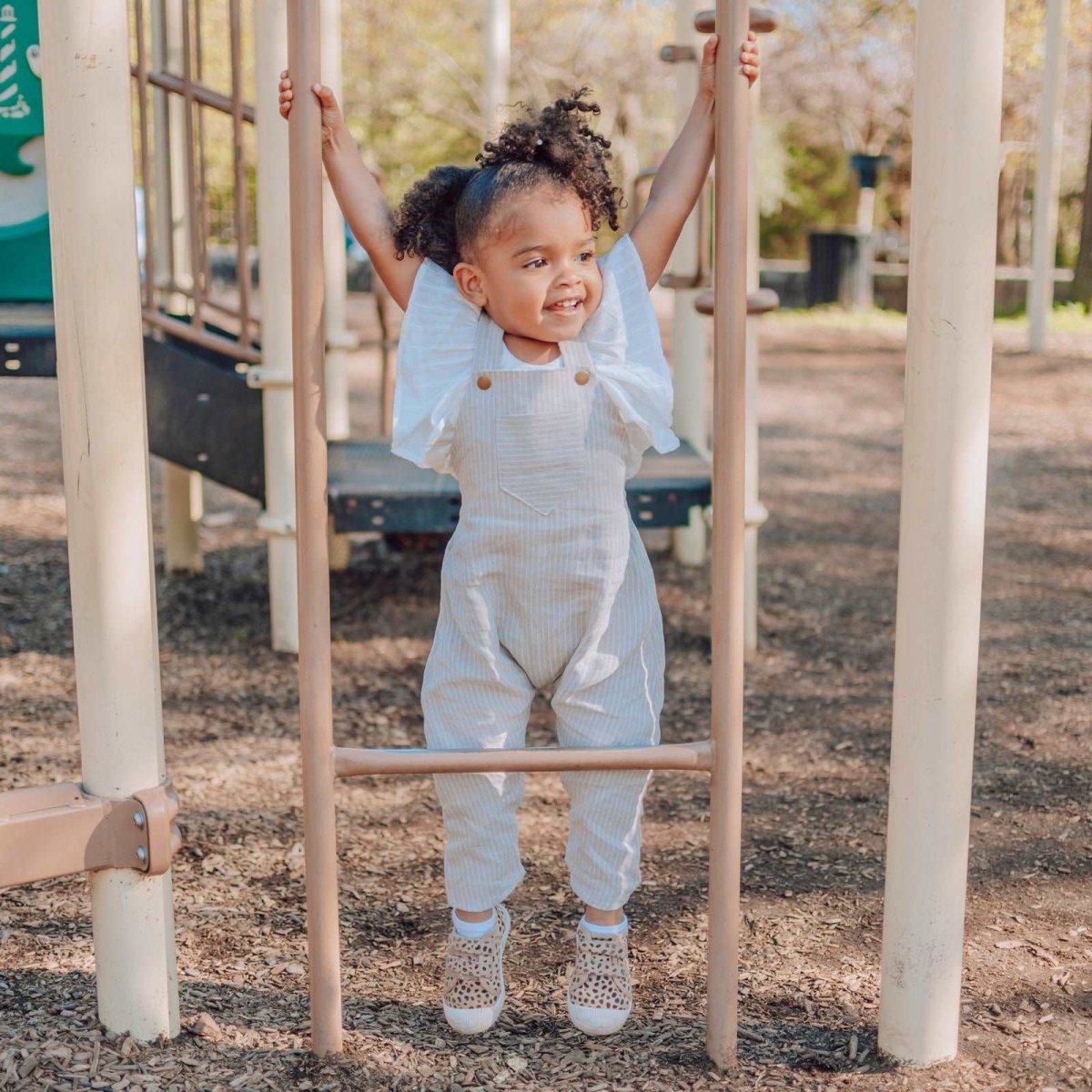 Photo of 2 year old Black child wearing a Beya Made harem romper playing on the playground