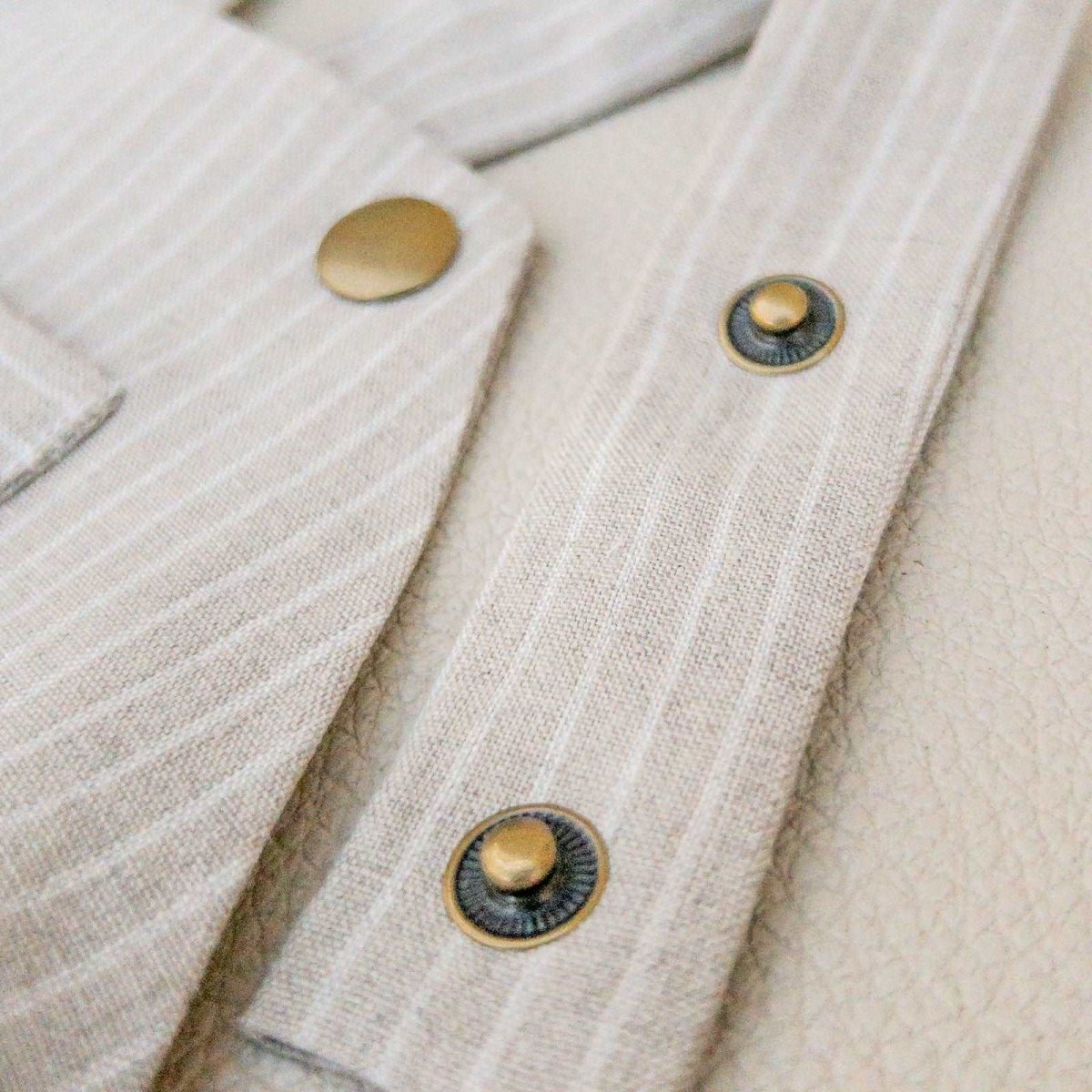 detail shot of multiple rows of snaps on the straps of a beige linen baby romper