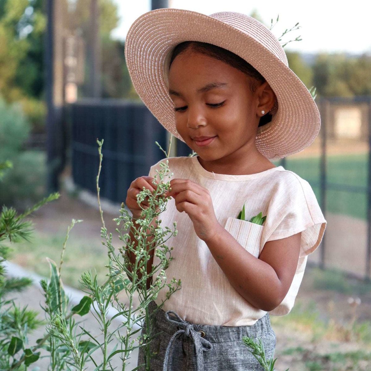 short sleeve linen box top worn by 3 year old girl shown touching flowers in a meadow